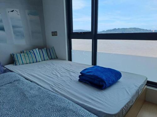 a bed with a blue pillow on it in a room with a window at Best moments in Kuantan