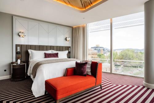 a bedroom with a large bed and a red chair at The Tasman, a Luxury Collection Hotel, Hobart in Hobart