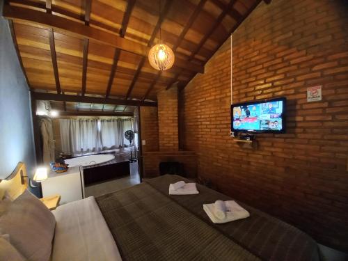 a bedroom with a bed and a tv on a brick wall at Pousada Visconde de Mauá in Visconde De Maua