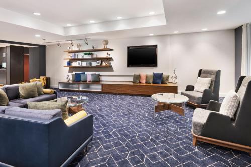 a living room with couches and a flat screen tv at Courtyard by Marriott Burlington in Burlington