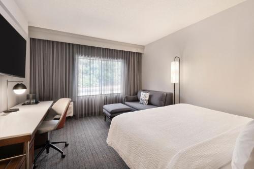 バーリントンにあるCourtyard by Marriott Burlingtonのベッドとデスクが備わるホテルルームです。