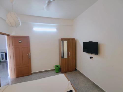 a room with a bed and a tv and a door at Retaj Residency in Ernakulam