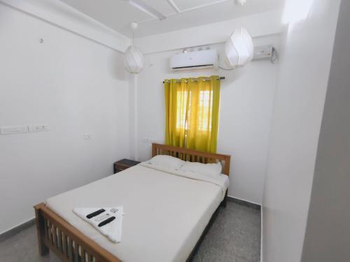 a small bedroom with a bed and a yellow curtain at Retaj Residency in Ernakulam