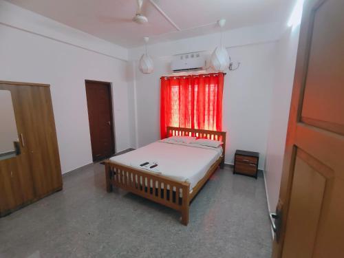 a bedroom with a bed and a red curtain at Retaj Residency in Ernakulam