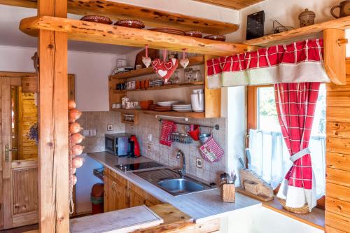 eine Küche in einem Blockhaus mit einem Waschbecken und einem Fenster in der Unterkunft Chalupa u Žofky in Oščadnica