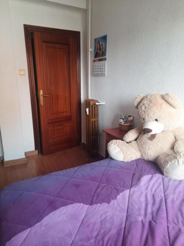 ein großer Teddybär auf einem Bett in der Unterkunft Una Habitación Individual en casa familiar dentro de Ciudad Patrimonio de la Humanidad in Alcalá de Henares