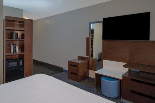 a hotel room with a bed and a flat screen tv at Fairfield Inn & Suites Houston Katy in Katy