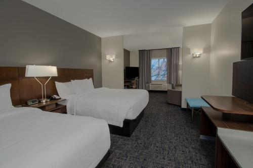 a hotel room with two beds and a flat screen tv at Fairfield Inn & Suites Houston Katy in Katy