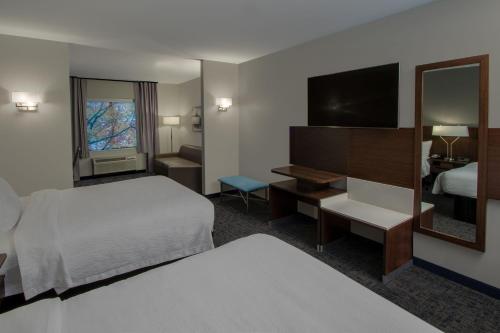 a hotel room with a bed and a mirror at Fairfield Inn & Suites Houston Katy in Katy