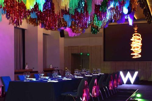 a room with a long table with chairs and colorful lights at W Melbourne in Melbourne