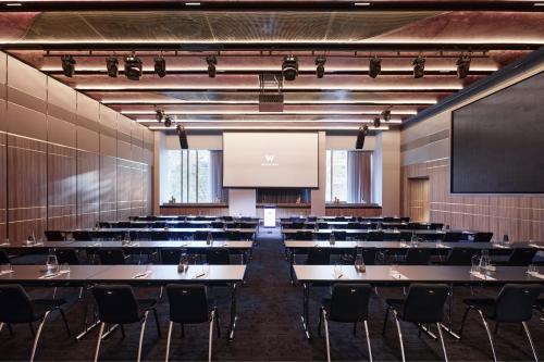 a conference room with tables and chairs and a screen at W Melbourne in Melbourne
