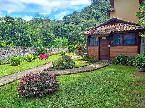 a house with a garden with flowers in the yard at Pousada Visconde de Mauá in Visconde De Maua