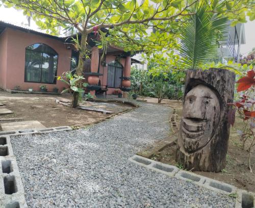 a head carved into a tree stump in front of a house at Micheck beach house in Tortuguero