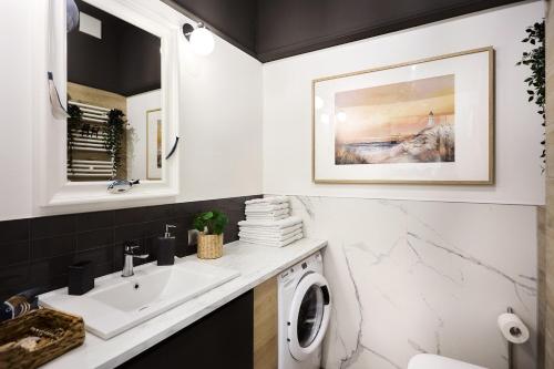 a bathroom with a sink and a washing machine at Golden Hour Apartments - Platan Tower in Świnoujście
