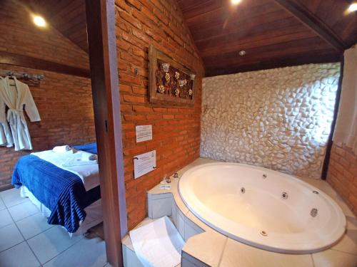 a bathroom with a bath tub and a bed at Pousada Visconde de Mauá in Visconde De Maua