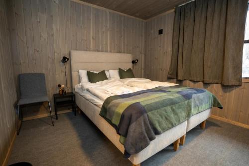 a bedroom with a bed and a chair and a window at Fulufjellet in Ljørdal