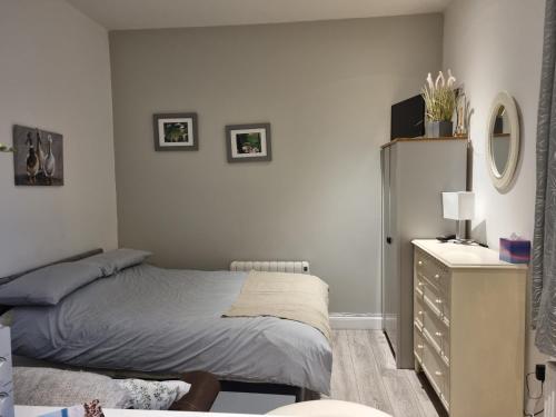a small bedroom with a bed and a dresser at Cracatinni Mews in Roundwood