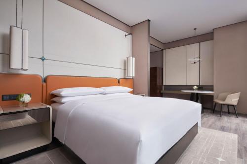 a bedroom with a large white bed and a table at Tianjin Marriott Hotel National Convention and Exhibition Center in Tianjin