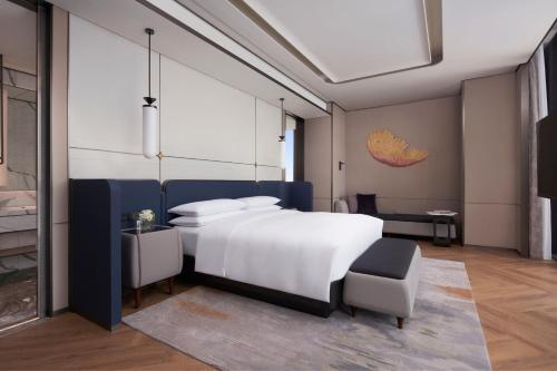 天津市にあるTianjin Marriott Hotel National Convention and Exhibition Centerのベッドルーム(大きな白いベッド1台、椅子付)