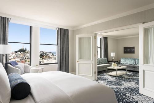 サンフランシスコにあるザ リッツ カールトン - サンフランシスコのベッドルーム(大きな白いベッド1台付)、リビングルームが備わります。