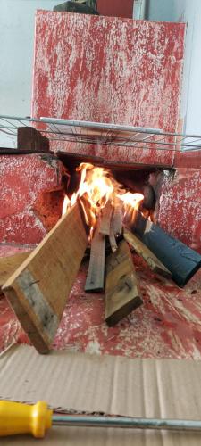 a fire in a pizza oven with some wood at HOSTEL BADULACK in Capitólio