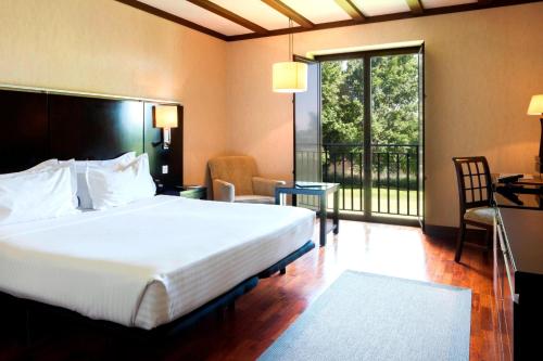 a bedroom with a large bed and a balcony at AC Hotel Palacio de Santa Ana by Marriott in Valladolid