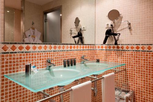 a bathroom with two sinks and a mirror at AC Hotel Palacio de Santa Ana by Marriott in Valladolid