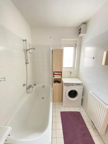 ein Badezimmer mit einer Badewanne und einer Waschmaschine in der Unterkunft cozy apartment close to vienna in Brunn am Gebirge