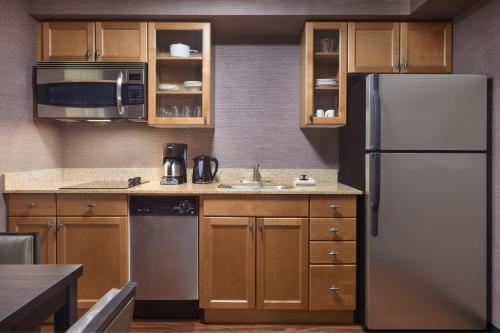 a kitchen with a stainless steel refrigerator and wooden cabinets at Residence Inn by Marriott London Canada in London