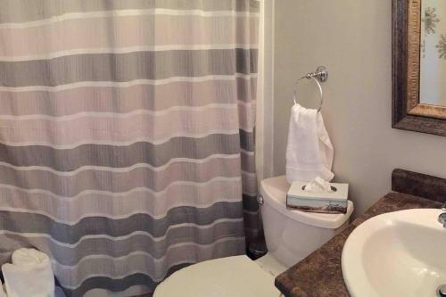 a bathroom with a shower curtain and a toilet and a sink at Mill Hill Haven in Victoria