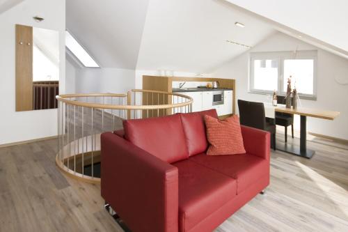 a living room with a red couch and a table at Birkhofer See genießen - Aparthotel am Bodensee in Immenstaad am Bodensee