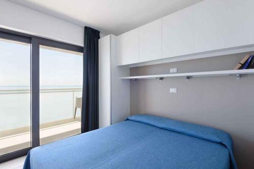 una camera con un letto blu e una grande finestra di Apartments in Lignano 21632 a Lignano Sabbiadoro