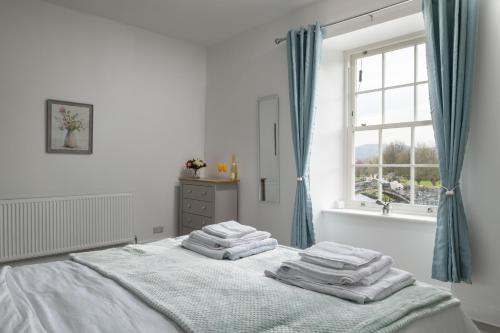 a white bedroom with a bed with towels on it at Glan Conwy House One and Two Bedroom Apartments in Llanrwst