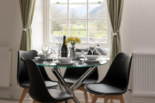 a dining room table with chairs and a window at Glan Conwy House One and Two Bedroom Apartments in Llanrwst
