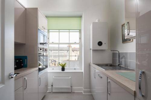 een witte keuken met een wastafel en een raam bij Glan Conwy House One and Two Bedroom Apartments in Llanrwst