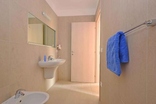 a bathroom with a white sink and a blue towel at Apartments in Lignano 21707 in Lignano Sabbiadoro