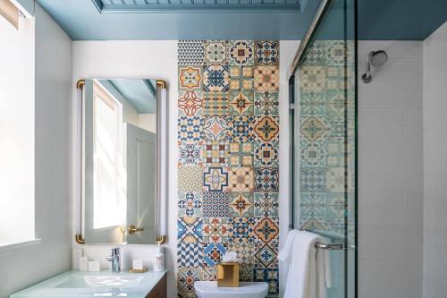 a bathroom with a shower and a sink and a mirror at Fenway Hotel, Autograph Collection in Dunedin