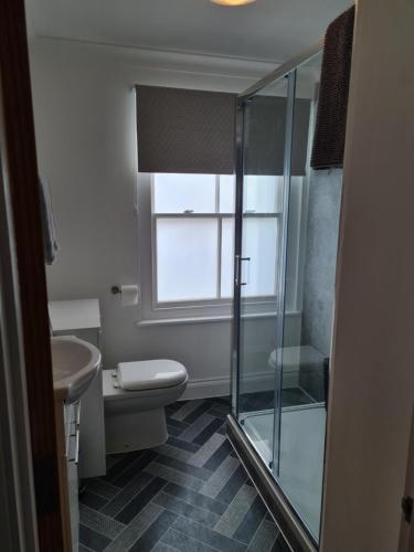 a bathroom with a toilet and a glass shower at Beautiful Apartment 3 Mins To The Beach in St. Leonards