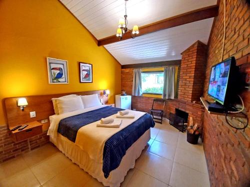 a bedroom with a large bed and a tv in it at Pousada Visconde de Mauá in Visconde De Maua