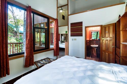 a bedroom with a bed and windows and a bathroom at Mariposa Jungle Lodge in San Ignacio