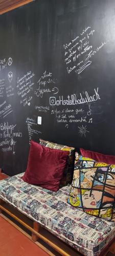 a chalkboard wall with a bed with writing on it at HOSTEL BADULACK in Capitólio