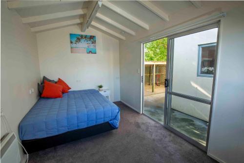 ein Schlafzimmer mit einem blauen Bett und einer Glasschiebetür in der Unterkunft Two-Storey Apartment Main Street in Methven