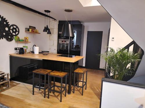 eine Küche mit einer Theke und Hockern in einem Zimmer in der Unterkunft CAPUCINE in Bourges