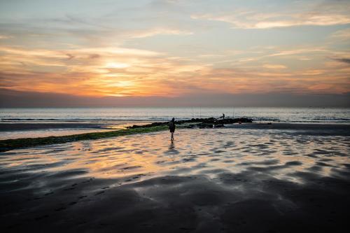 a person standing on the beach at sunset at les Cabanes d'Ostende in Ostend