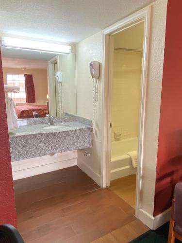 a bathroom with a tub and a sink and a mirror at Travel Inn lackland Sea World in San Antonio