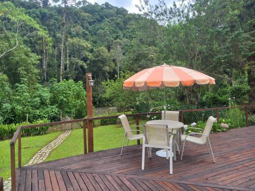 a table and chairs on a wooden deck with an umbrella at Pousada Visconde de Mauá in Visconde De Maua
