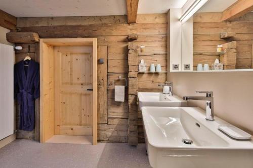 un bagno con pareti in legno, lavandino e porta di Haus zum Reh a Krummenau
