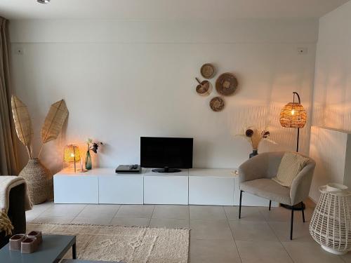 a living room with a tv and a chair at Apartment Zin in Zee in Knokke-Heist