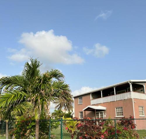 a building with a palm tree in front of it at Fortescue Cherry Blossom Apartments in Saint Philip