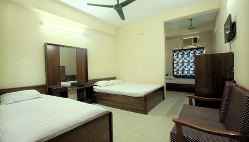 Pokój z 2 łóżkami, krzesłem i lustrem w obiekcie Hotel Sea Queen w mieście Koks Badźar